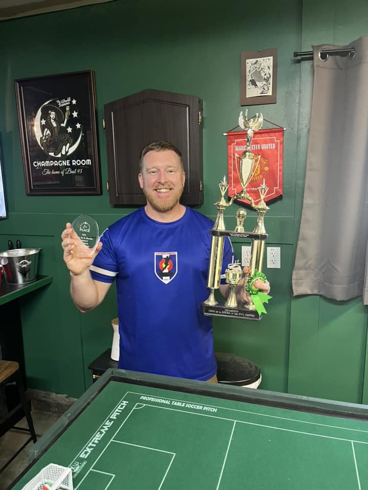 Man in blue shirt standing with a trophy